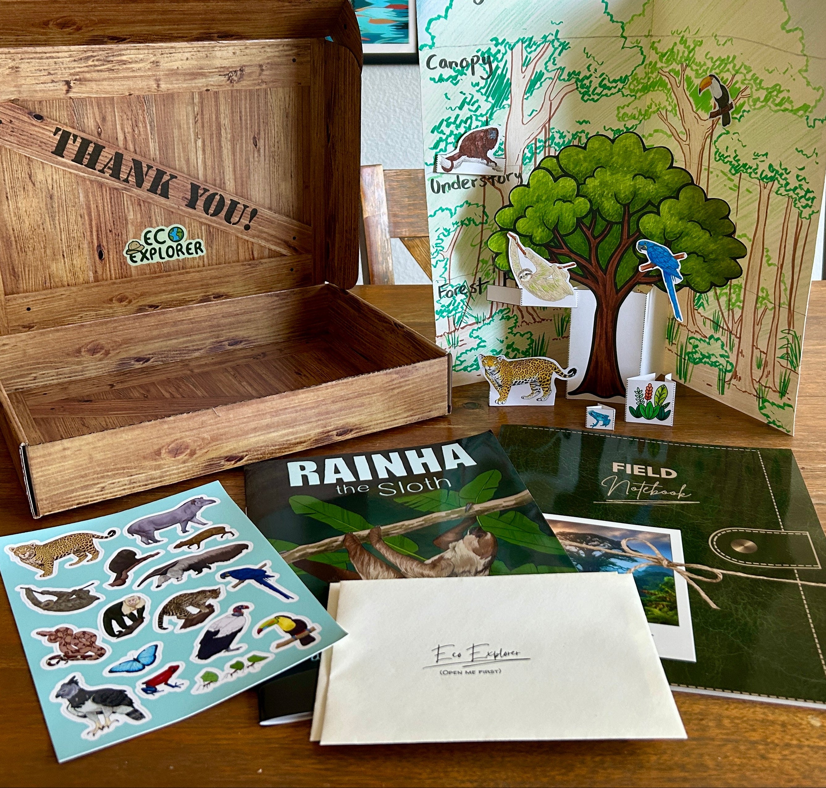 Educational materials including a wooden box, field notebook, and animal stickers on a table.